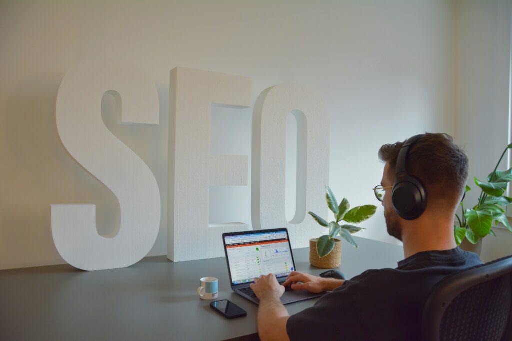 Person working on SEO analysis using a laptop with SEO letters displayed in the background